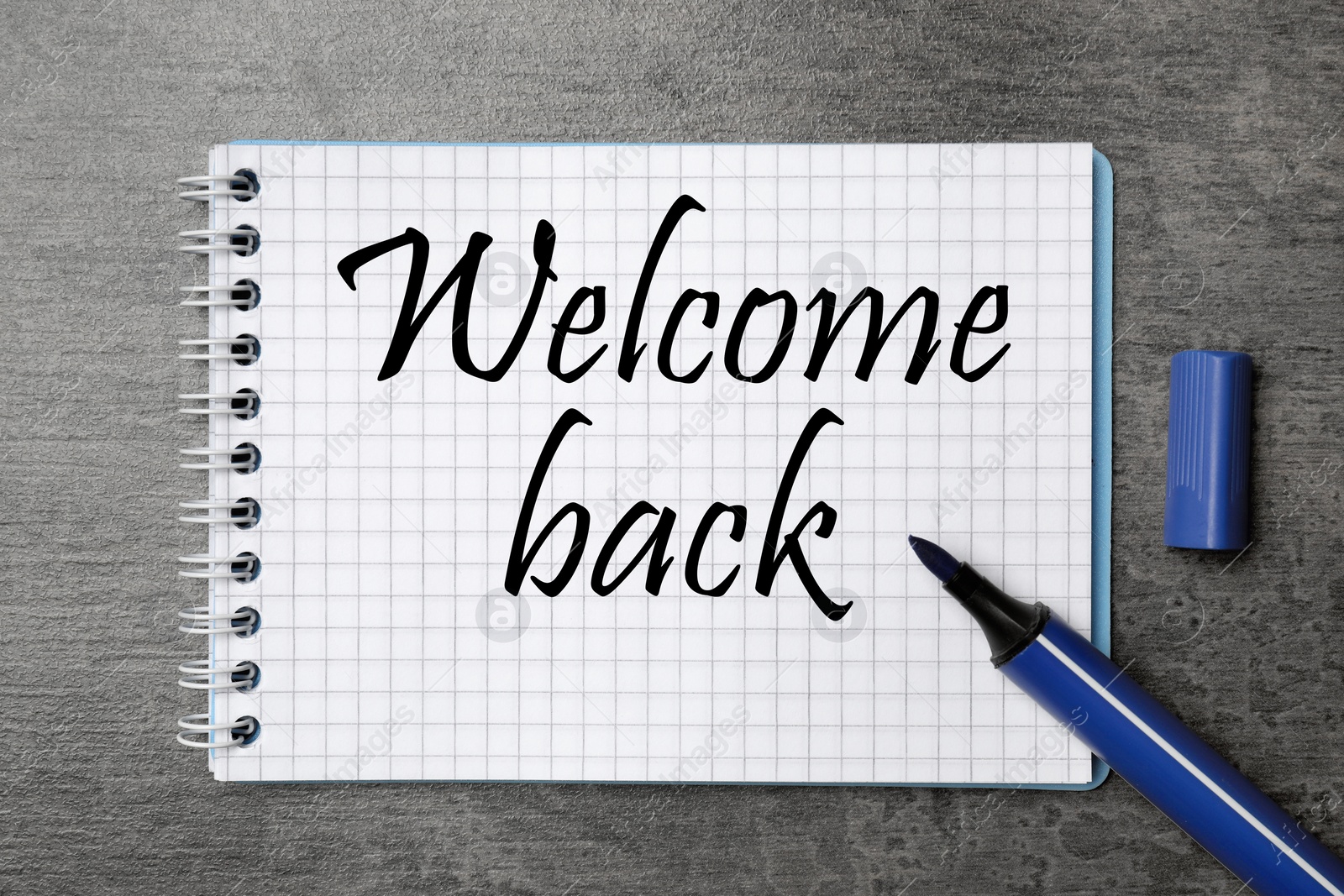 Image of Notebook with phrase Welcome Back and felt tip pen on grey table, top view