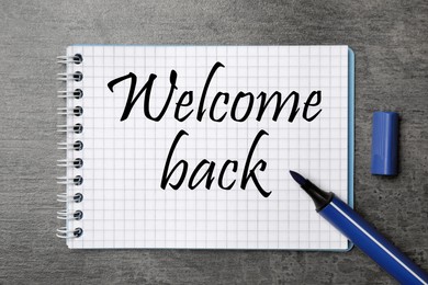 Image of Notebook with phrase Welcome Back and felt tip pen on grey table, top view