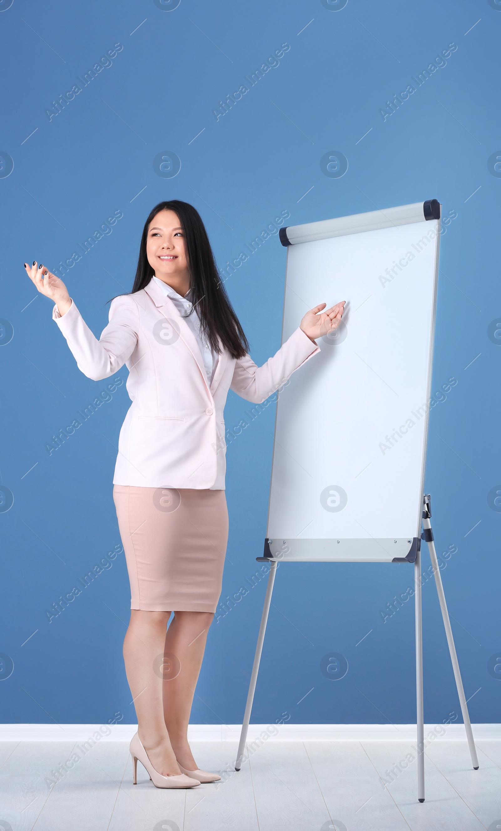 Photo of Business trainer giving presentation on flip chart board against color wall background