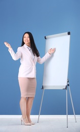 Business trainer giving presentation on flip chart board against color wall background