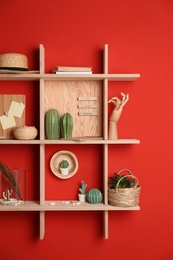 Stylish wooden shelves with decorative elements on red wall