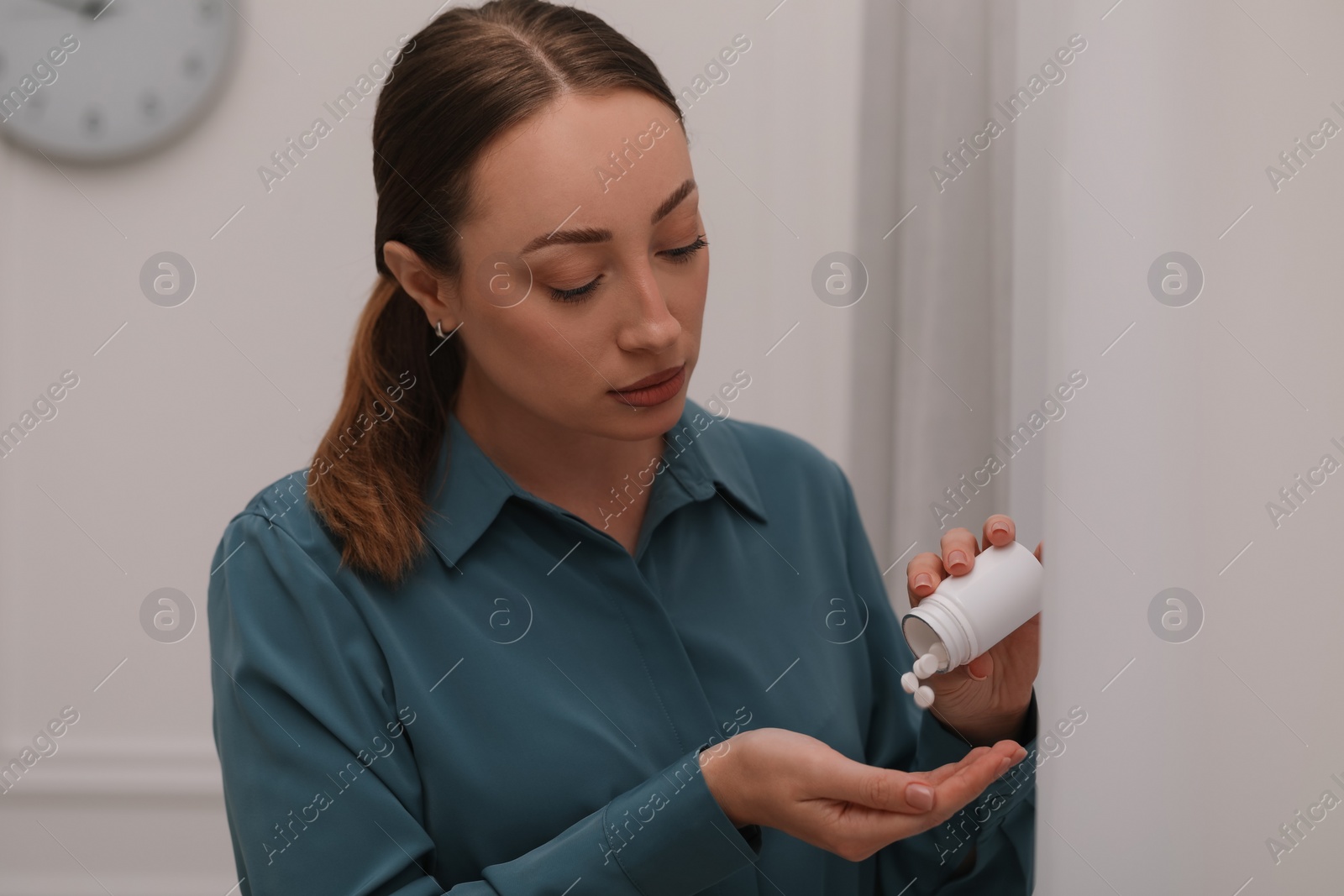 Photo of Young woman pouring antidepressants from bottle indoors