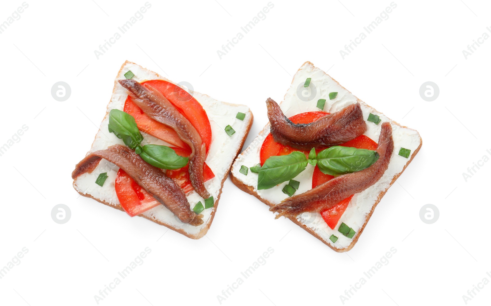 Photo of Delicious sandwiches with cream cheese, anchovies, tomatoes and basil on white background, top view