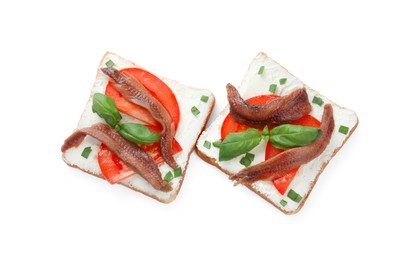 Delicious sandwiches with cream cheese, anchovies, tomatoes and basil on white background, top view