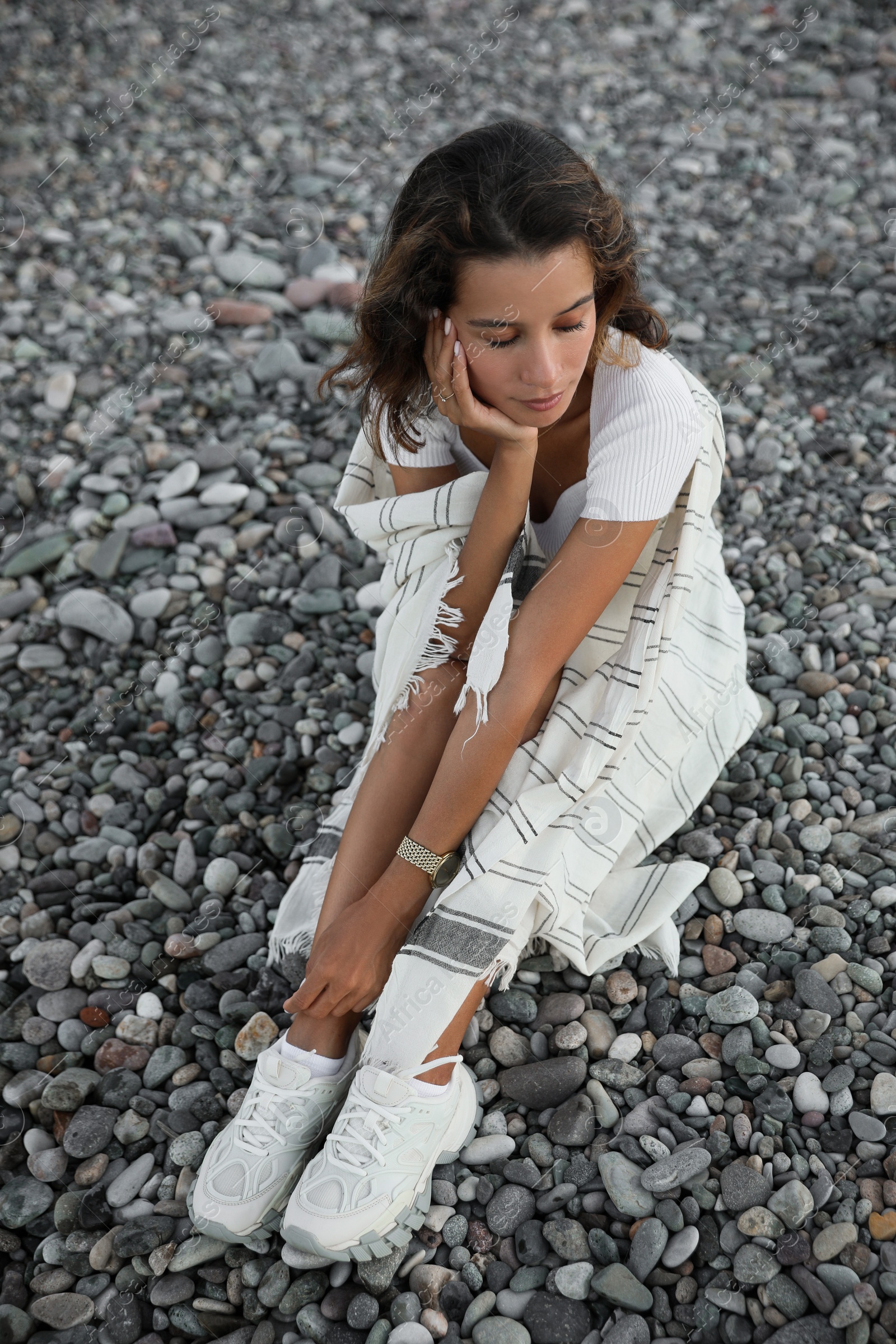 Photo of Beautiful young woman sitting on pebble beach