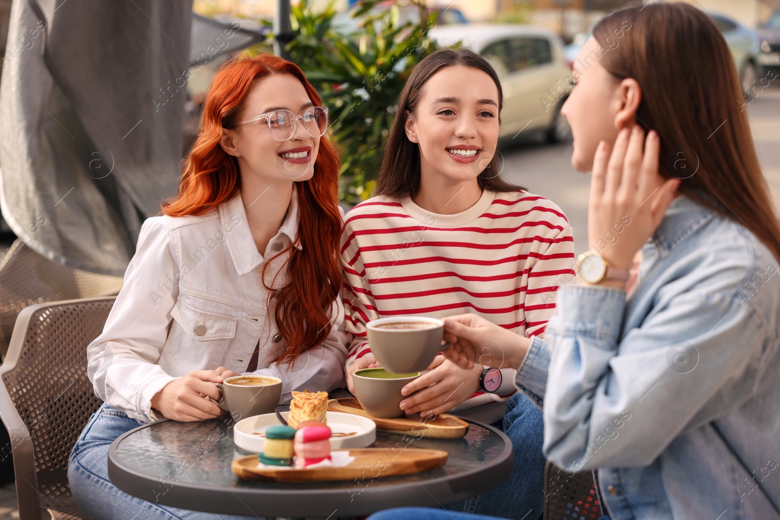 Photo of Happy friends talking and drinking coffee in outdoor cafe