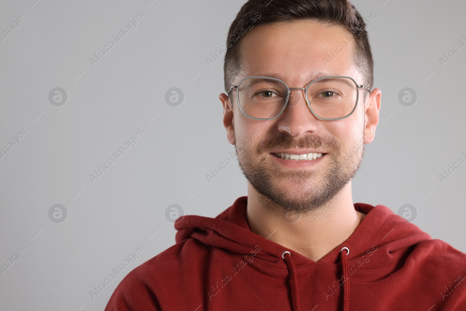 Photo of Portrait of happy man in stylish glasses on light grey background. Space for text