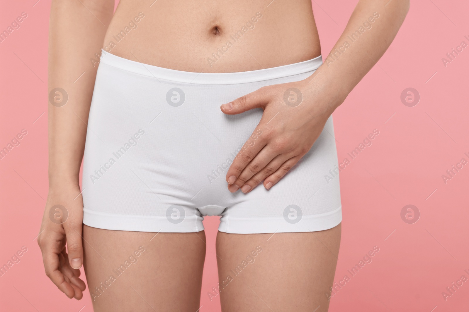 Photo of Woman holding hand near panties on pink background, closeup. Women's health