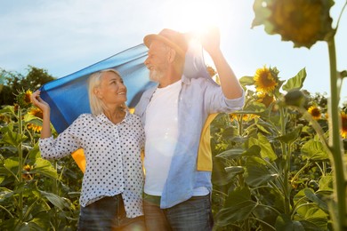 Photo of Happy mature couple with national flag of Ukraine in sunflower field