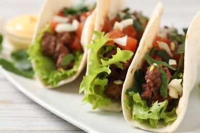 Delicious tacos with meat and vegetables on table, closeup