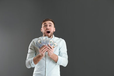 Photo of Portrait of emotional young man with money on grey background. Space for text