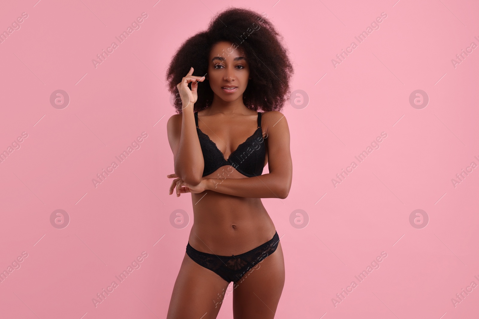 Photo of Beautiful woman in elegant black underwear on pink background