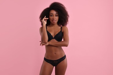 Photo of Beautiful woman in elegant black underwear on pink background