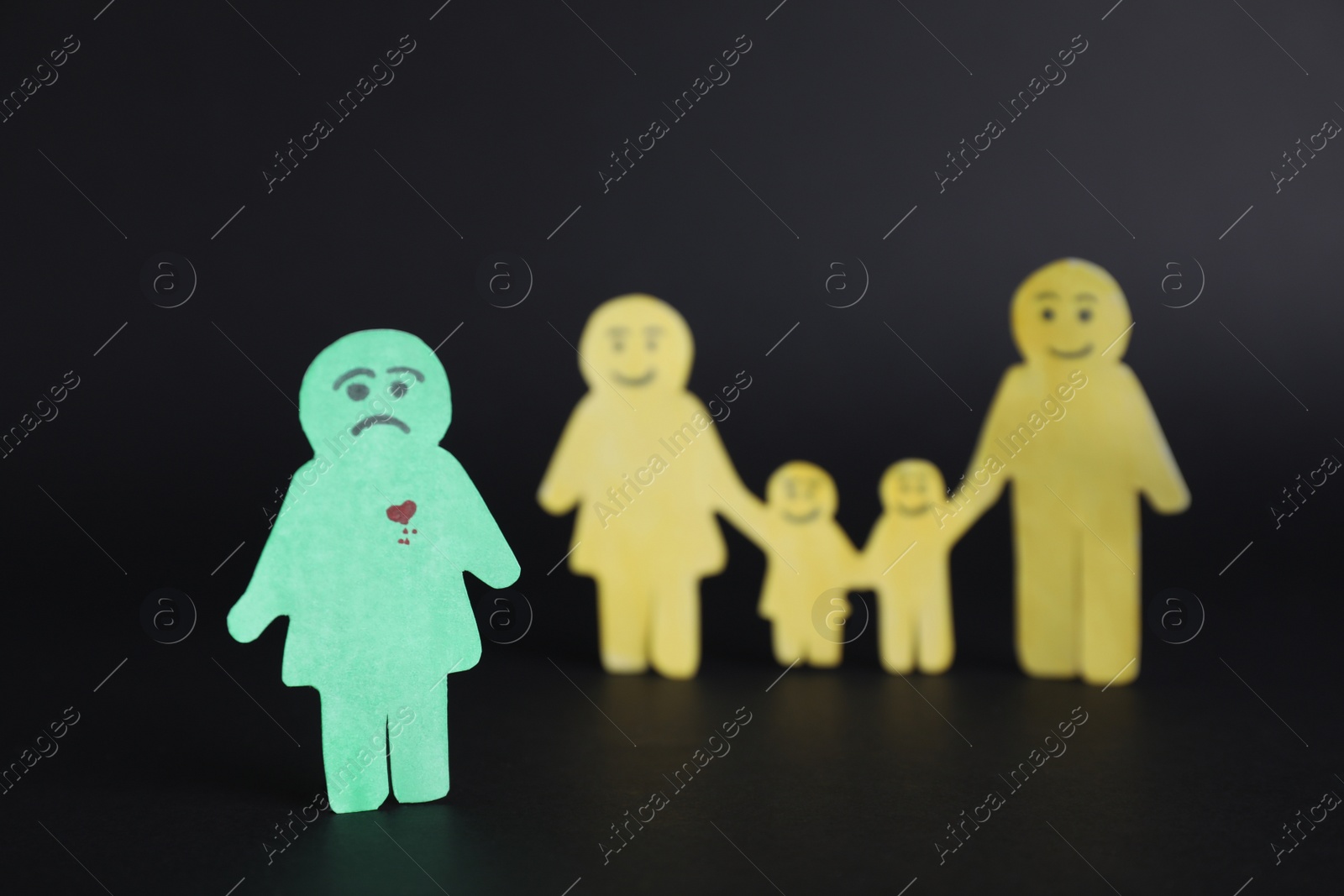 Photo of Human paper figures on black background. Concept of jealousy