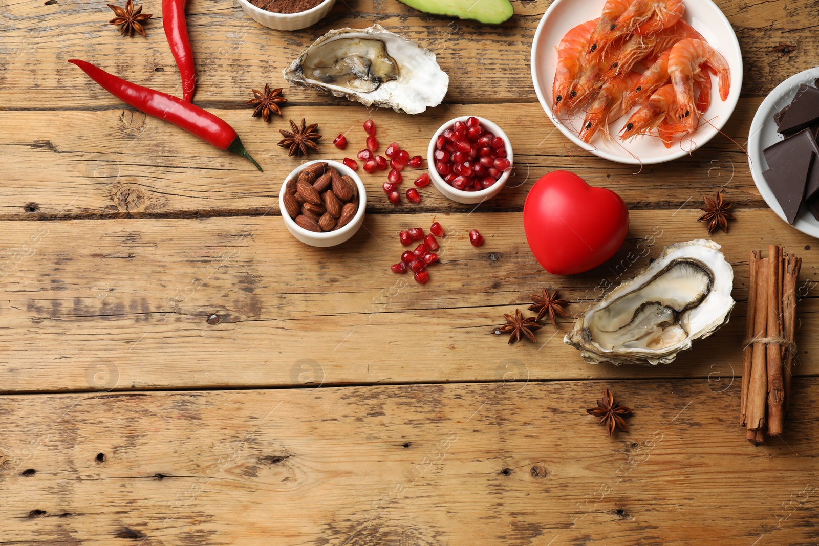 Photo of Natural aphrodisiac. Different food products and heart model on wooden table, flat lay. Space for text