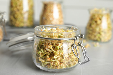 Photo of Glass jar of sprouted green buckwheat on light grey table