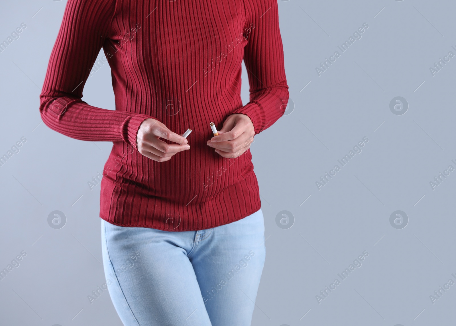Photo of Young pregnant woman breaking cigarette on grey background, closeup. Space for text