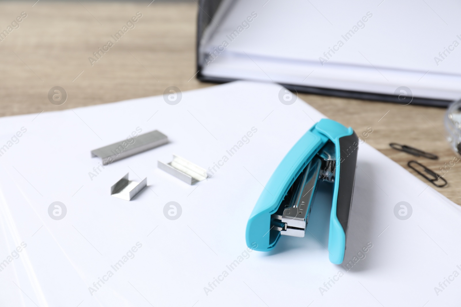 Photo of Stapler, paper and metal staples on table, closeup