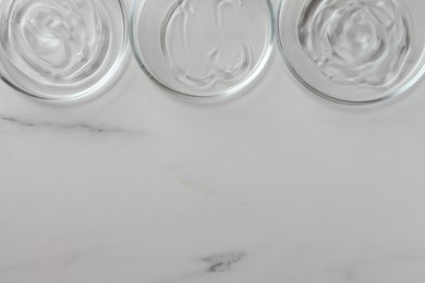 Photo of Petri dishes with liquids on white marble table, flat lay. Space for text