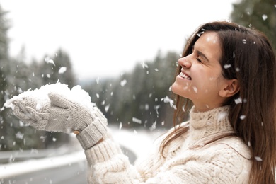 Young woman playing with snow outdoors. Winter vacation