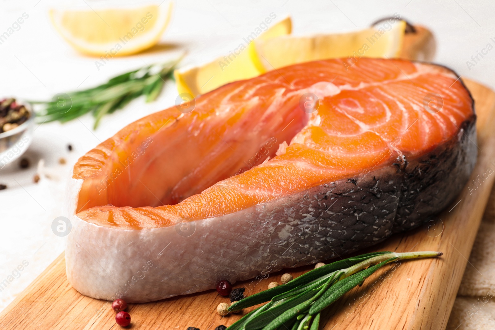 Photo of Fresh salmon steak with spices and rosemary on white table, closeup view