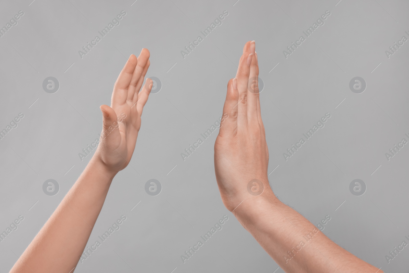 Photo of Mother and daughter giving high five on light grey background, closeup of hands