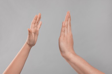 Mother and daughter giving high five on light grey background, closeup of hands