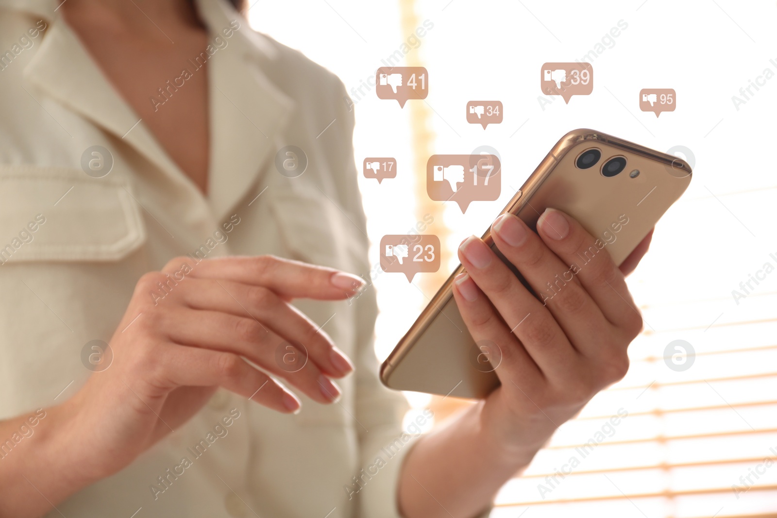 Image of Closeup view of young woman using modern smartphone indoors and virtual dislike icons. Cyberbullying concept