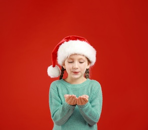 Image of Happy little child in Santa hat on red background. Christmas celebration