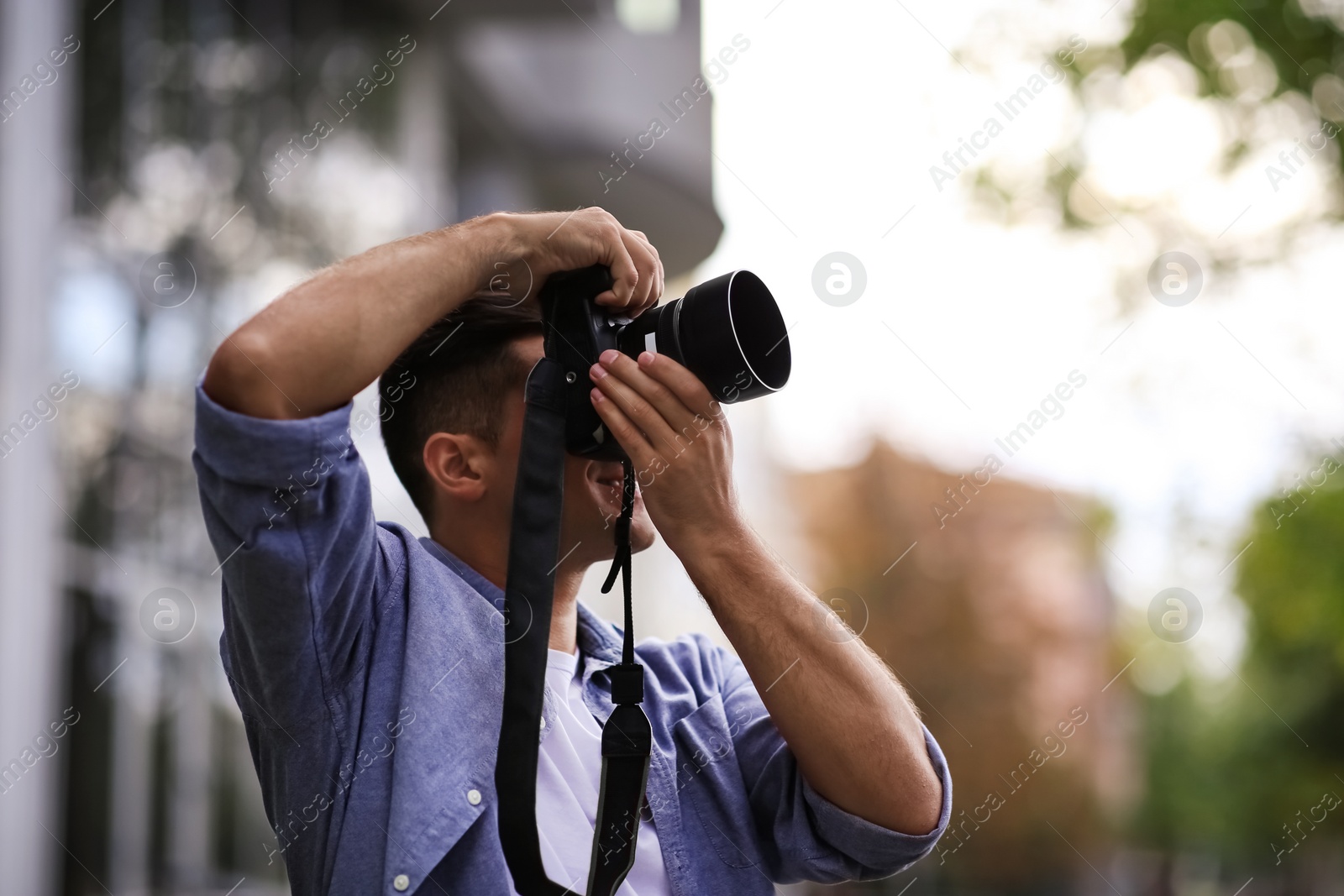 Photo of Photographer taking picture with professional camera on city street