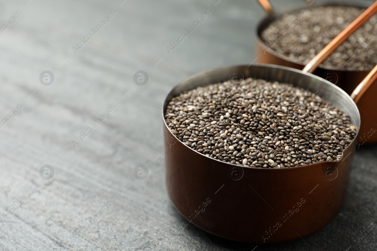 Photo of Saucepan with chia seeds on slate table. Space for text