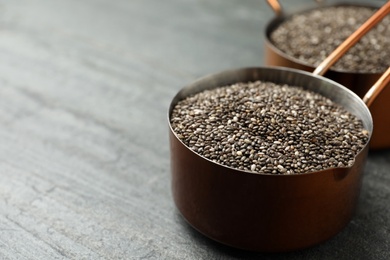 Photo of Saucepan with chia seeds on slate table. Space for text