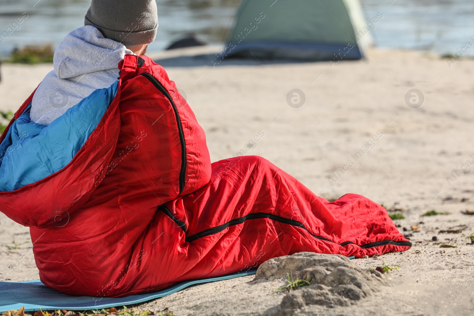Photo of Man in sleeping bag on wild beach. Space for text