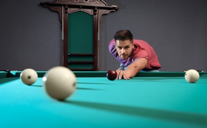 Photo of Handsome young man playing Russian billiard indoors