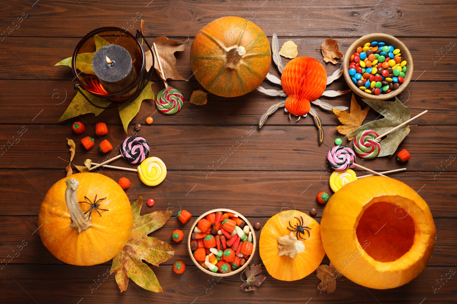 Photo of Flat lay composition with pumpkin head Jack lantern and Halloween treats on wooden background. Space for text