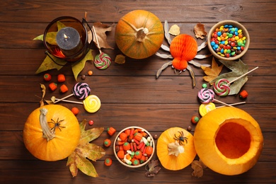 Photo of Flat lay composition with pumpkin head Jack lantern and Halloween treats on wooden background. Space for text