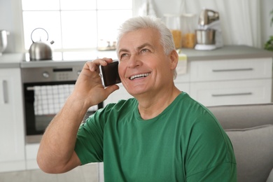 Mature man laughing while talking on phone at home