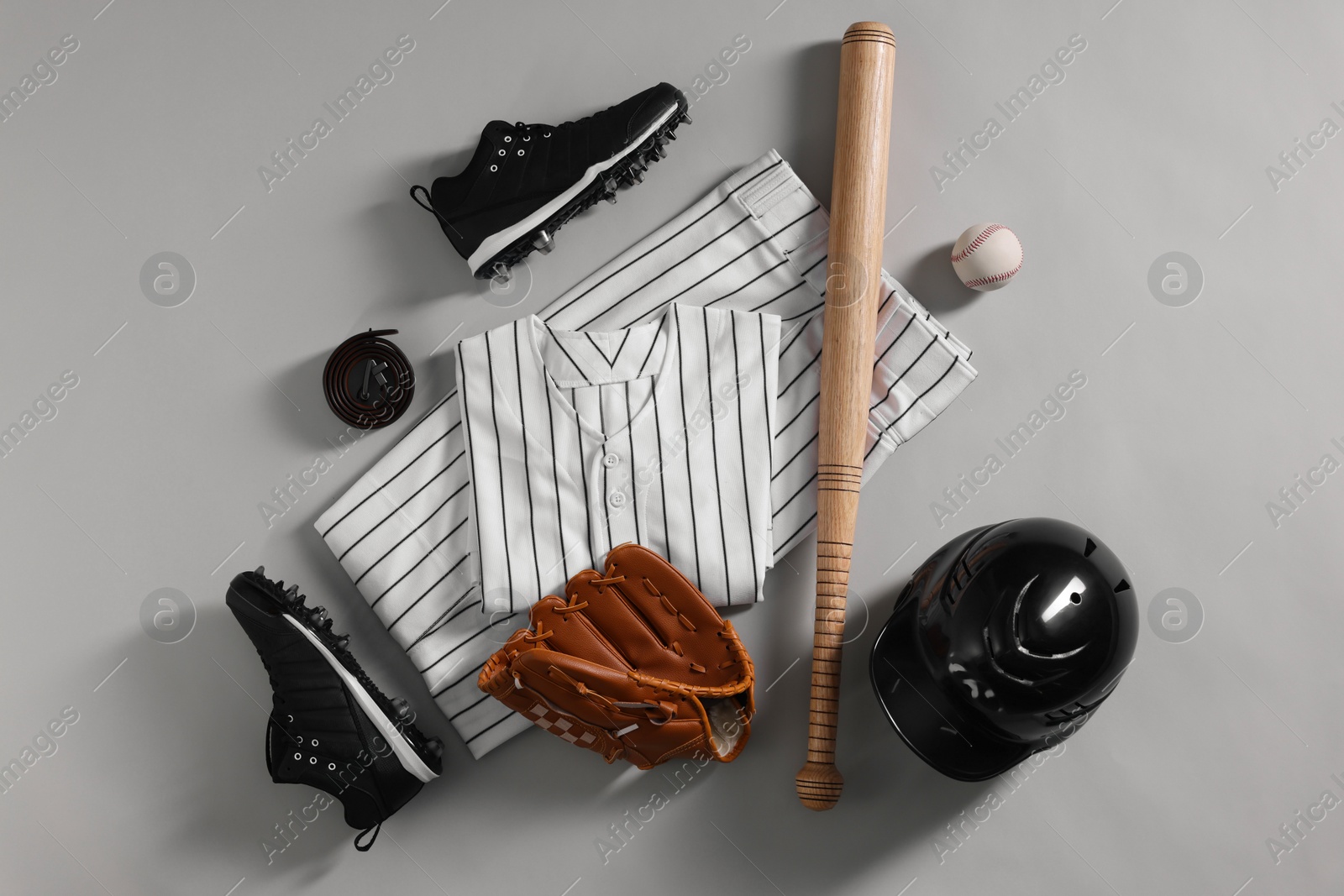 Photo of Baseball uniform and other sports equipment on white background, flat lay