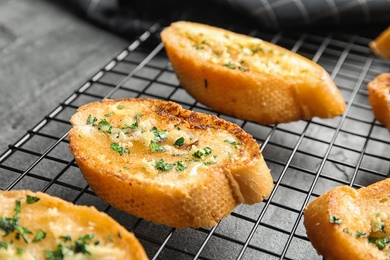 Baking rack with tasty homemade garlic bread on table, closeup