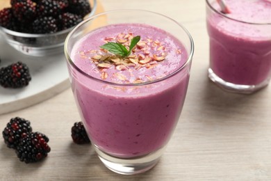 Photo of Delicious blackberry smoothie with oatmeal in glass on white wooden table, closeup