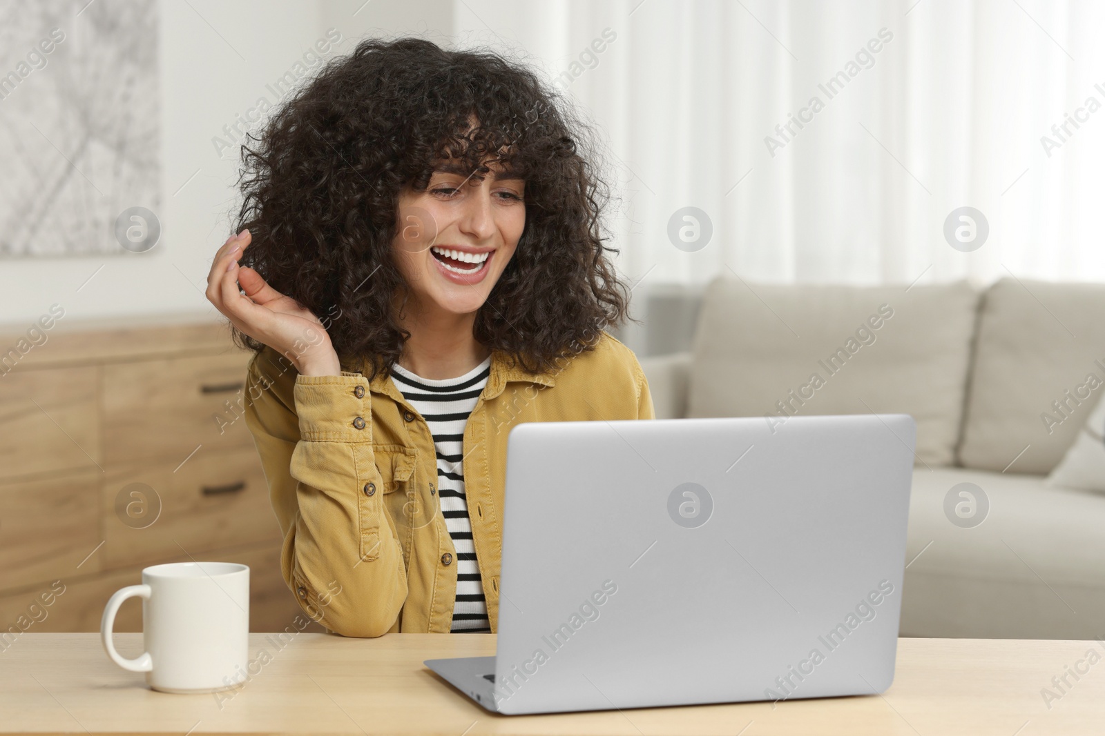 Photo of Happy woman having video chat via laptop at table in room