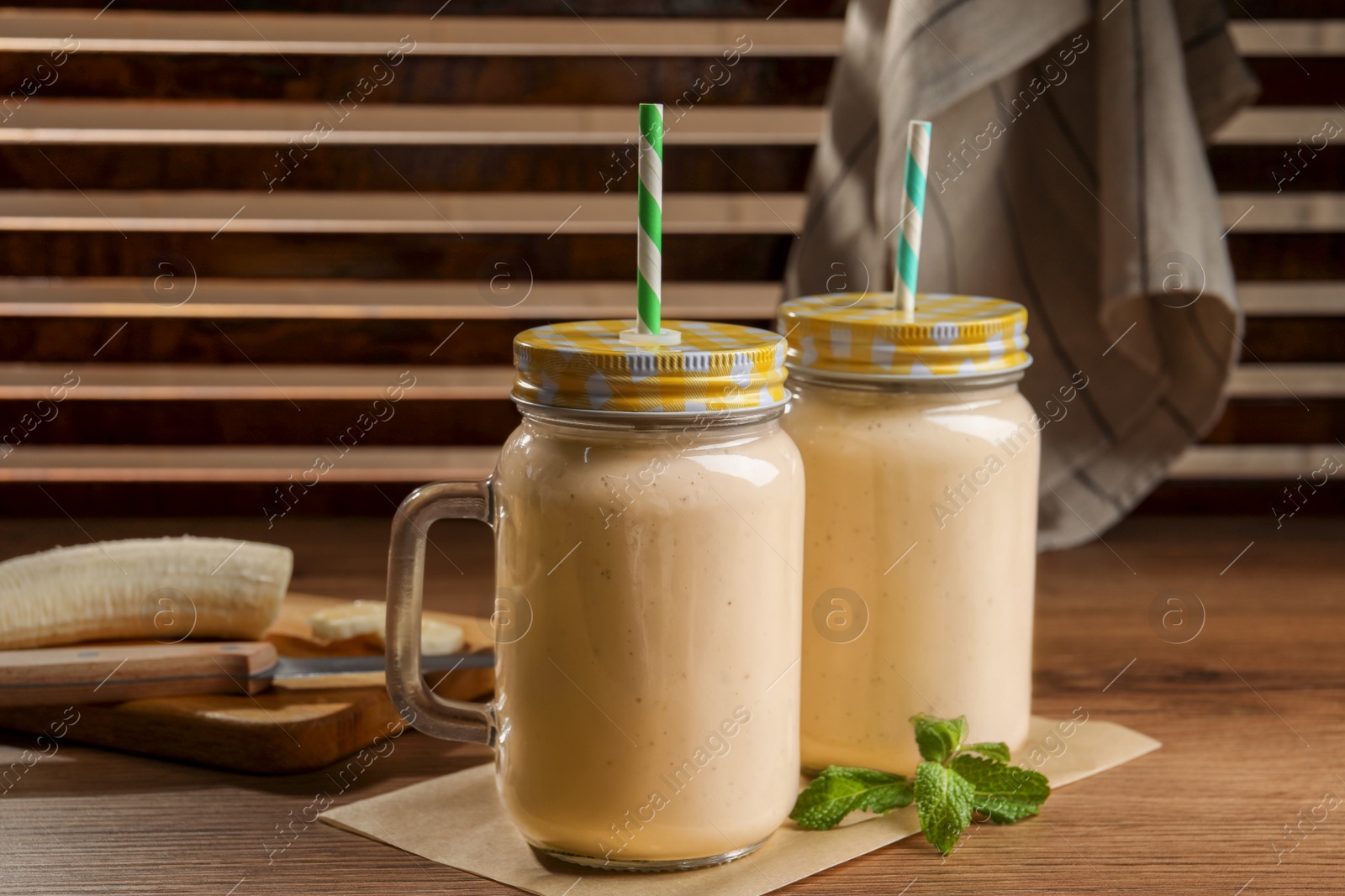 Photo of Tasty banana smoothie and mint on wooden table