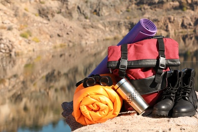 Set of camping equipment with sleeping bag on ground outdoors. Space for text