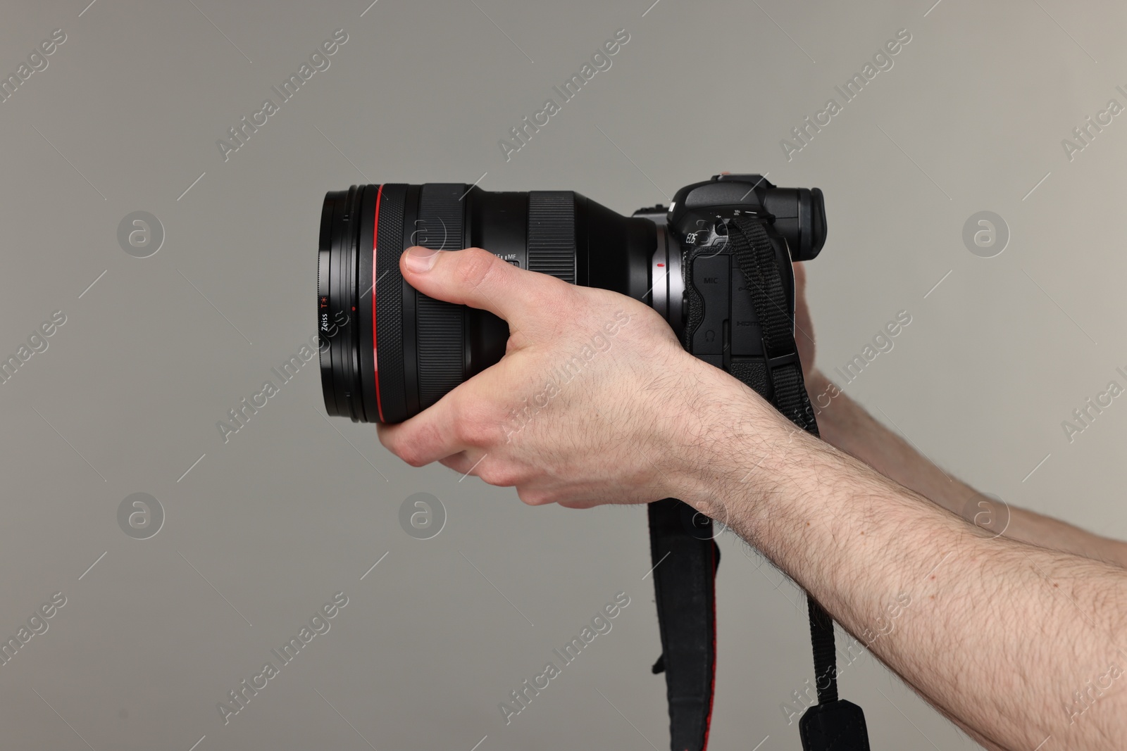 Photo of Photographer holding camera on grey background, closeup