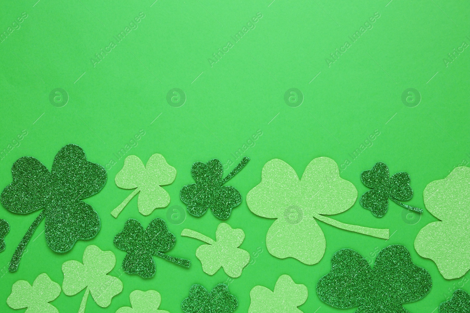 Photo of Decorative clover leaves on green background, flat lay with space for text. Saint Patrick's Day celebration