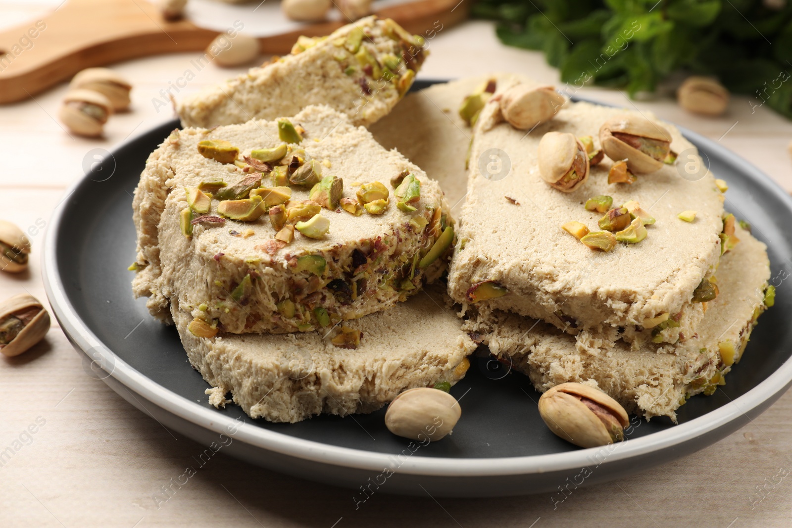 Photo of Pieces of tasty halva with pistachios on table, closeup