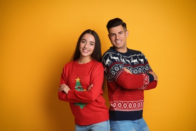 Couple in Christmas sweaters on yellow background