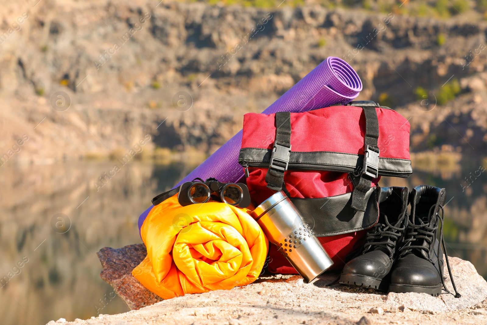 Photo of Set of camping equipment with sleeping bag on ground outdoors