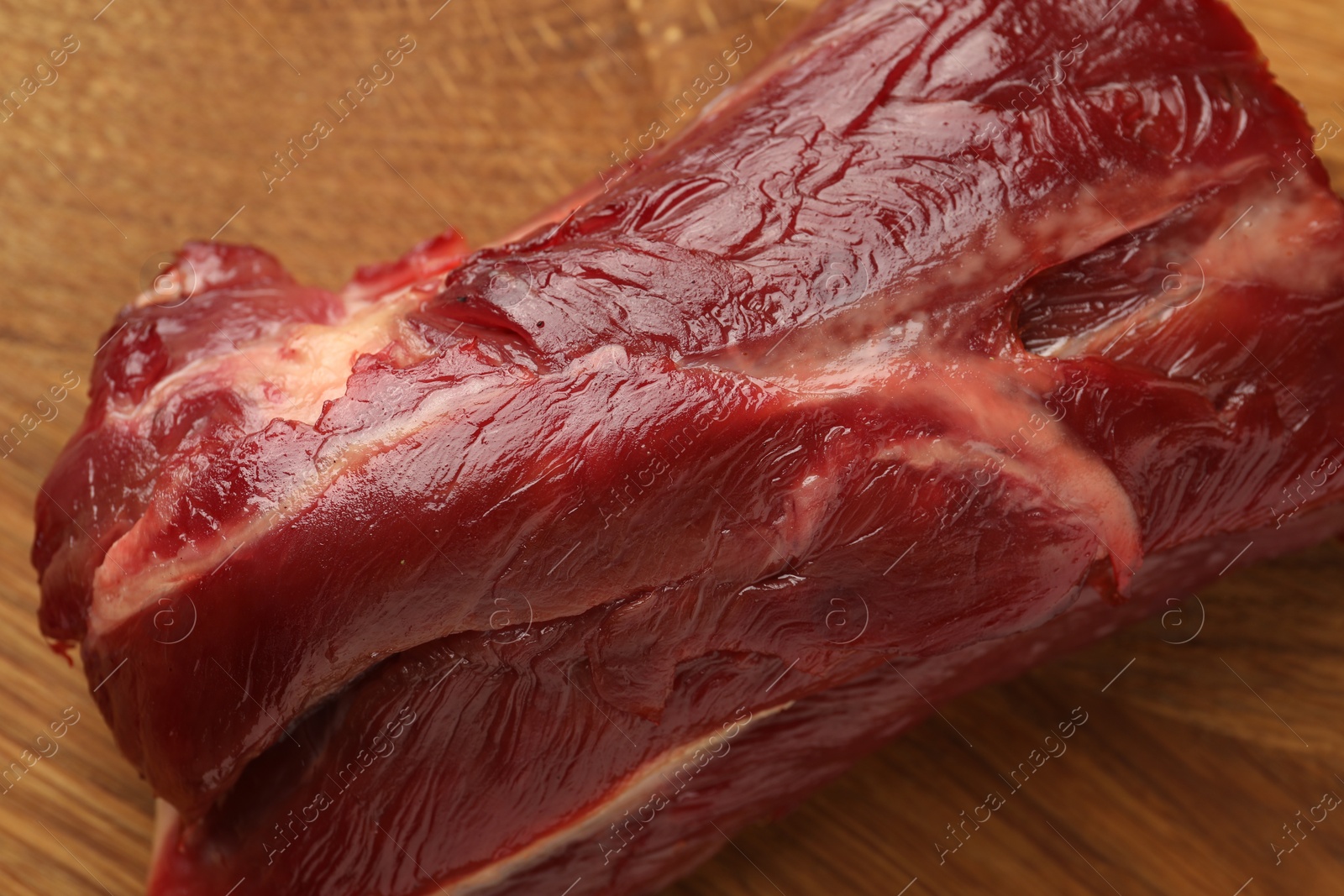 Photo of Piece of raw beef meat on wooden board, top view