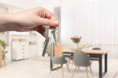 Woman holding house keys in room, closeup